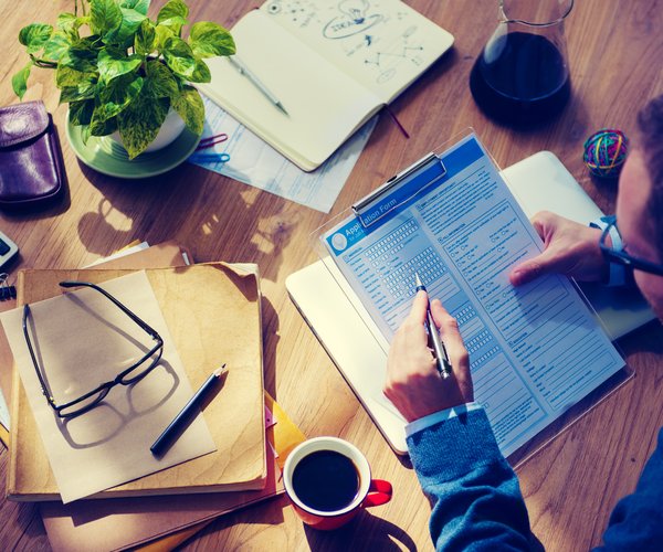 top-view-of-woman-holding-pen-near-document-with-visa-application-lettering-near-smartphone-with-e1692632864660.jpg